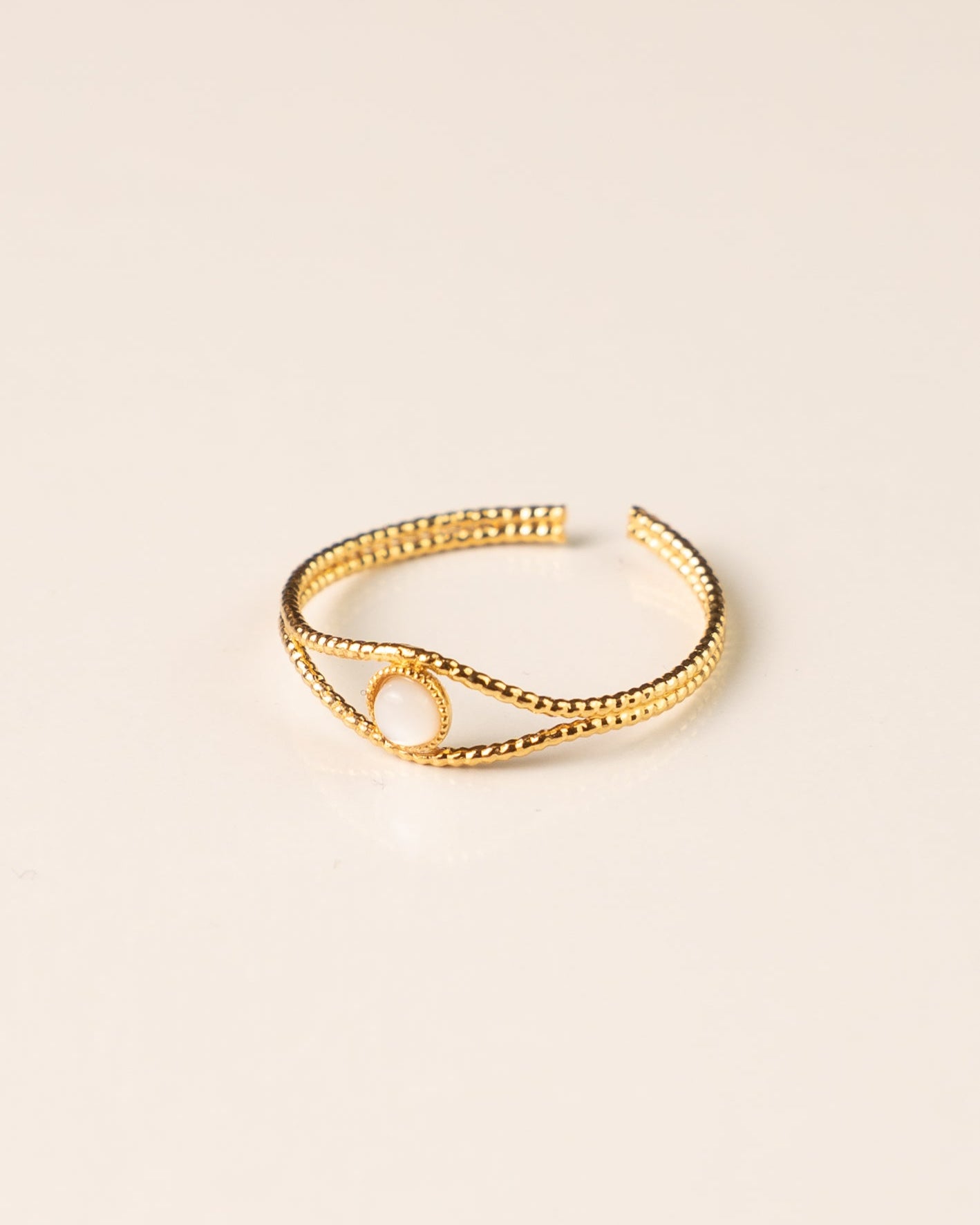 Bague ajustable en plaqué or avec une nacre blanche, design fin et texturé. Bijou tendance et délicat pour femme.