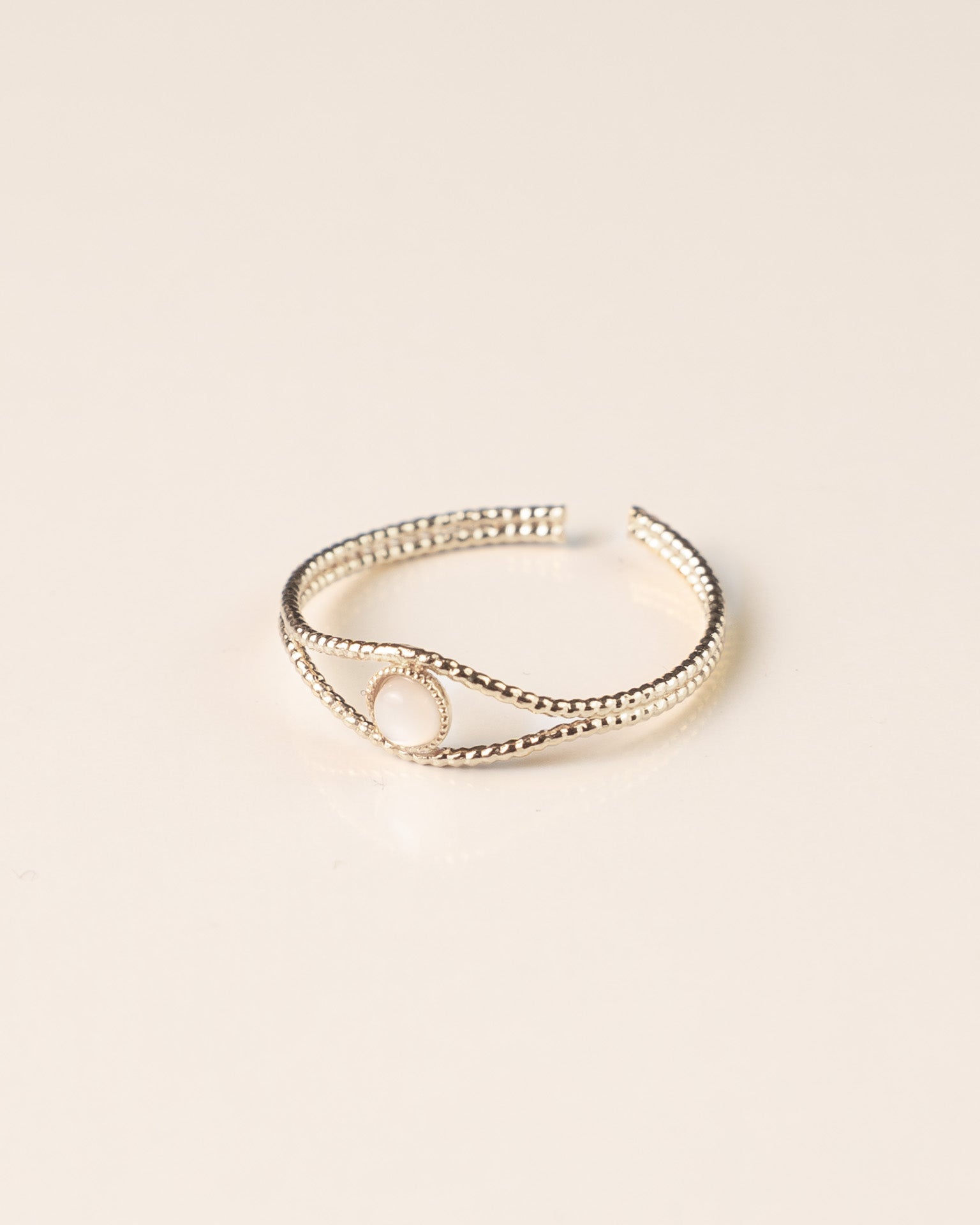 Bague ajustable en plaqué argent avec une nacre blanche, design fin et texturé. Bijou tendance et délicat pour femme.