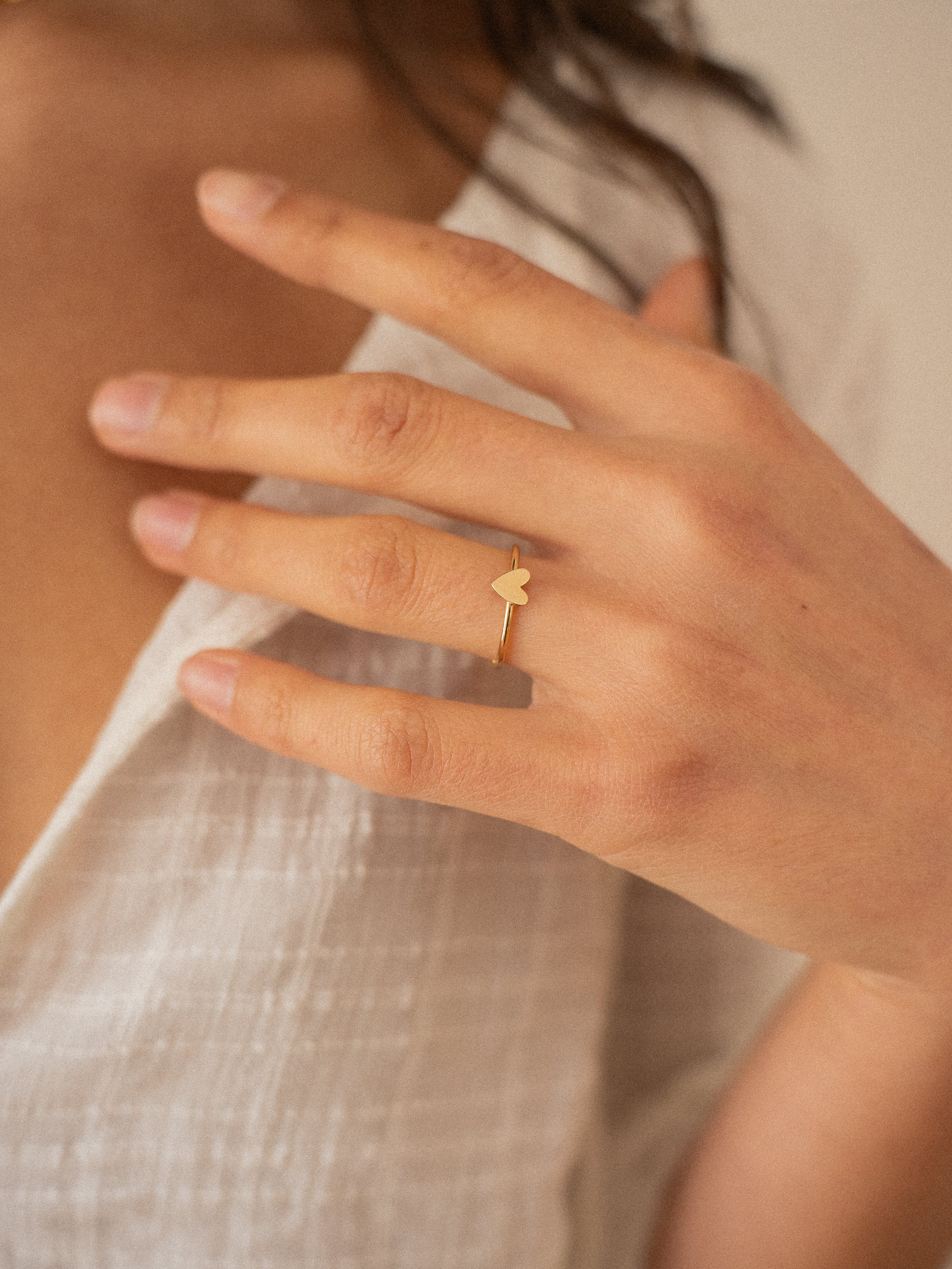 Bague fine en plaqué or avec un motif cœur minimaliste, portée sur une main féminine élégante. Bijou tendance idéal pour un look raffiné et romantique.