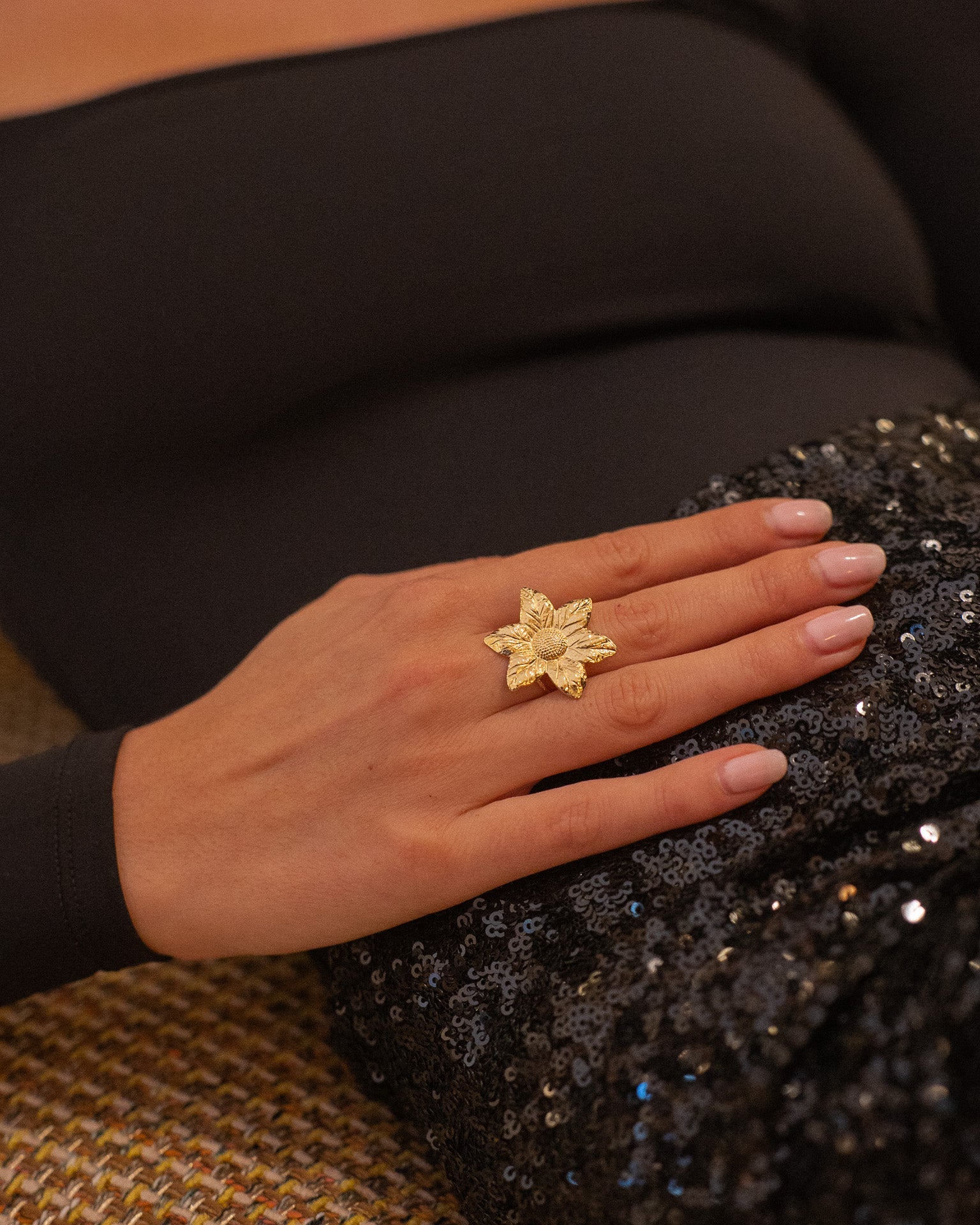 Main ornée d’une bague fleur en plaqué or. Bijou audacieux parfait pour une tenue de soirée élégante.